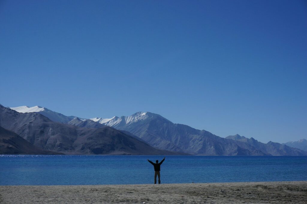 a person standing on a beach with their arms in the air