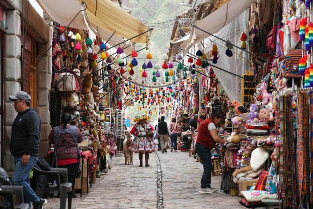 Colorful market stalls line a narrow cobblestone street.